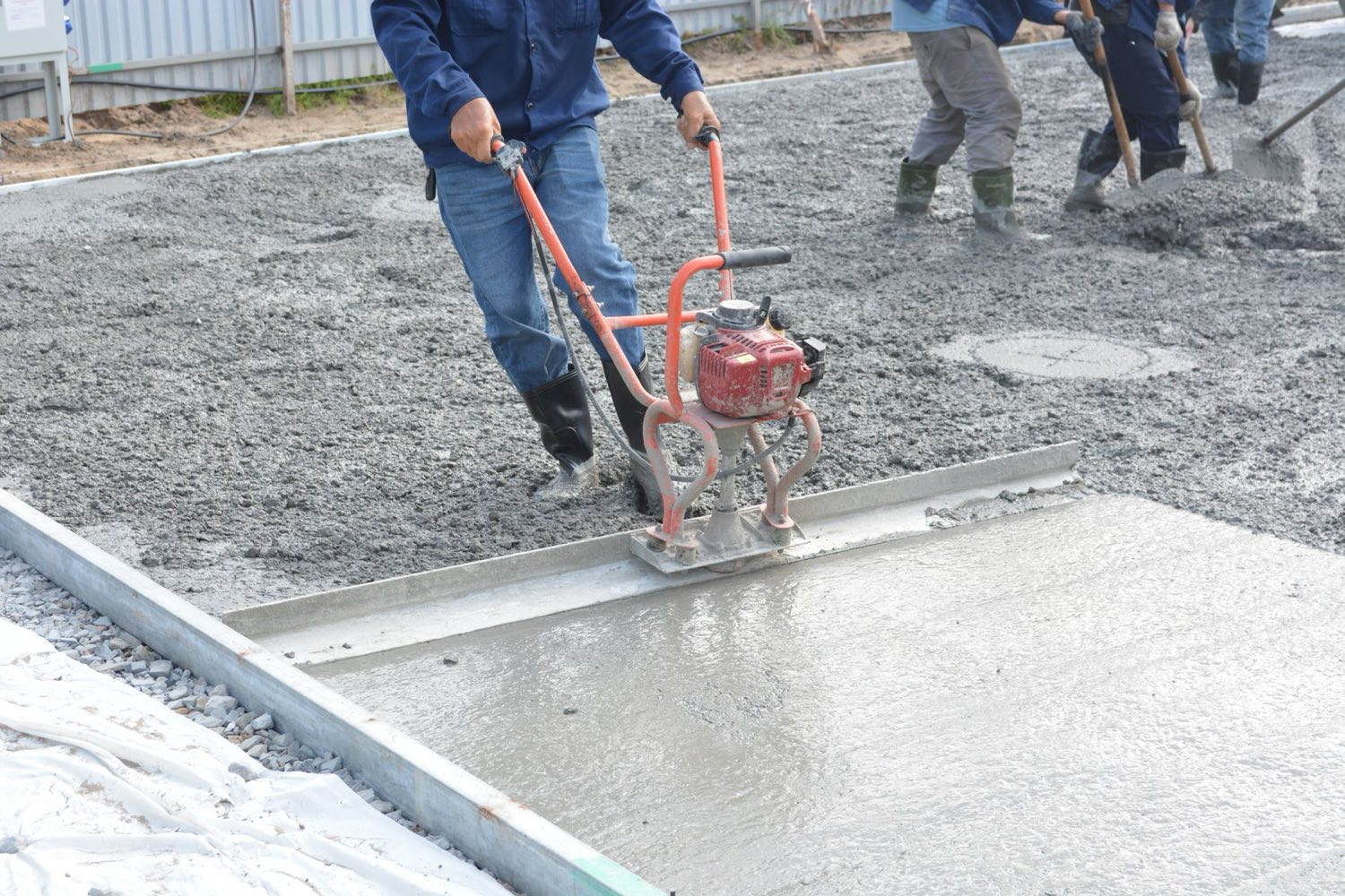 Crew screeding a fresh concrete slab across formwork